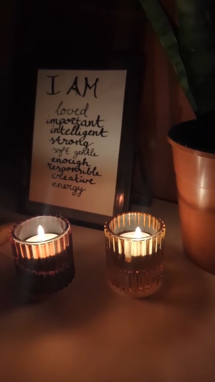 Twee brandende waxinelichtjes voor een handgeschreven kaart met 'I AM loved, important, intelligent, strong'